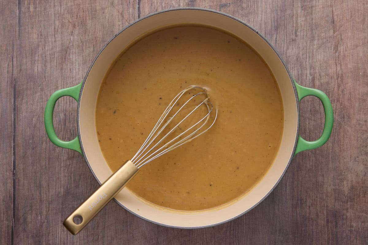 Gravy in a dutch oven with a whisk.