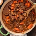 Green dutch oven filled with beef daube (french beef stew). Surrounded by salt and pepper bowls and fresh herbs.