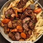 Grey pottery bowl filled with beef daube on pasta (French beef stew).
