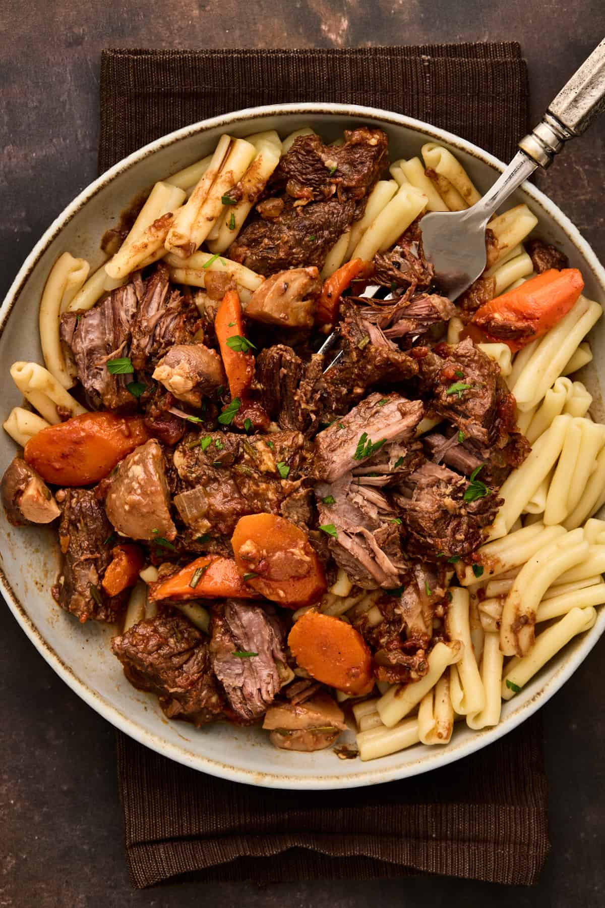 Gray ceramic bowl filled with pasta and beef daube (french beef stew).