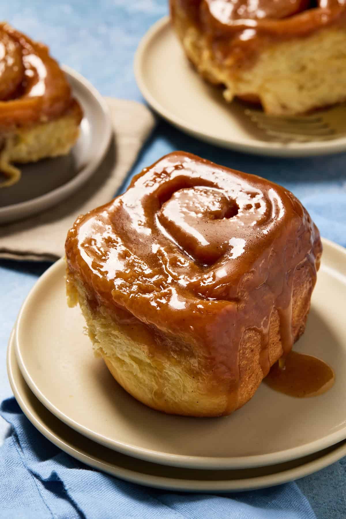 Caramel roll on a small plate with caramel oozing down the side.