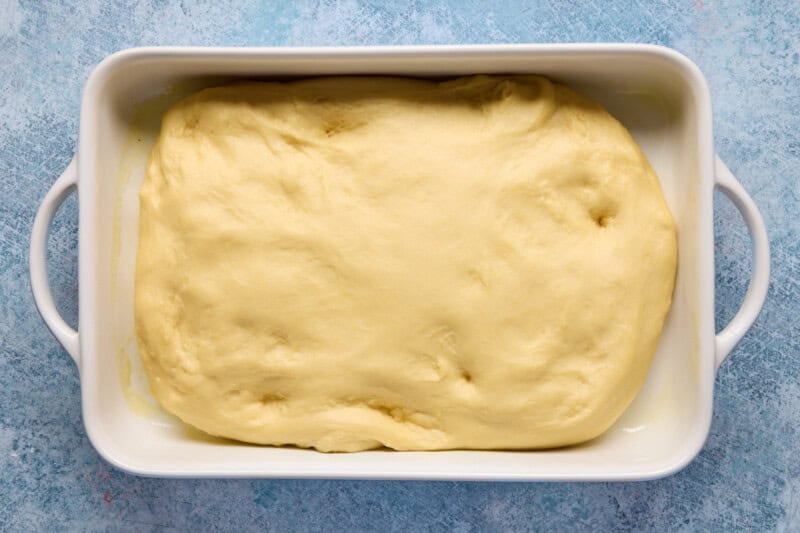 Risen caramel roll dough in a white casserole dish.