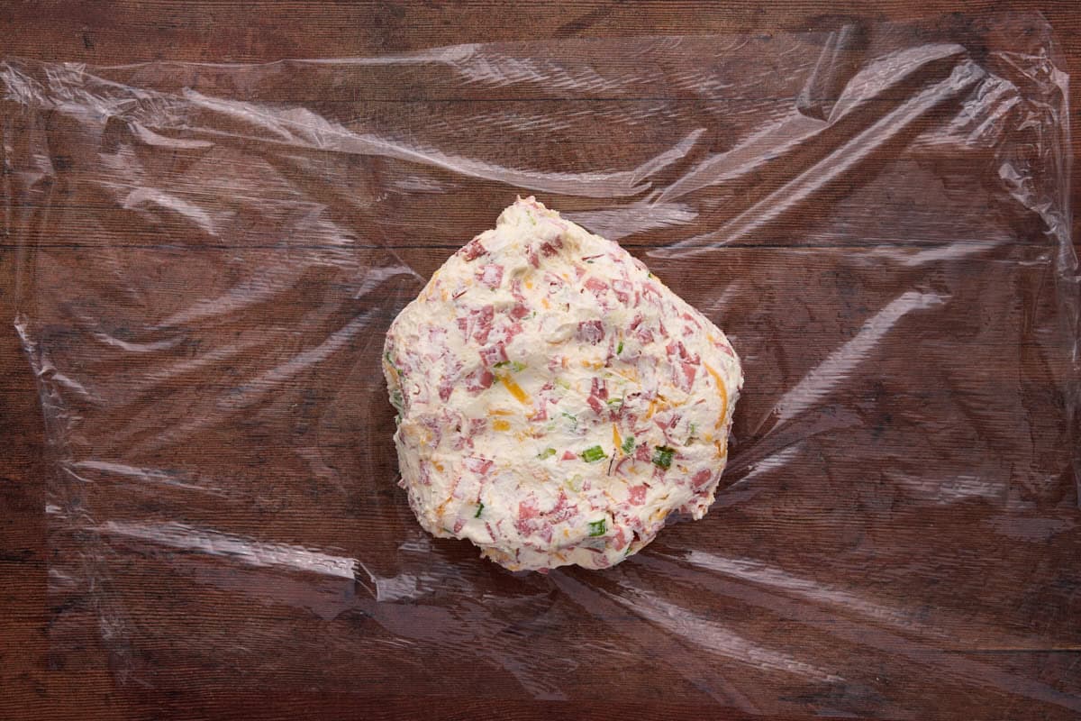 Cheese ball on plastic, ready to be shaped and chilled.