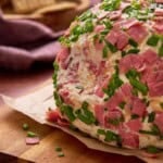 Chipped Beef Cheeseball with a scoop out on parchemnt with crackers.