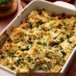 Over angle of crab dip with spinach and sun dried tomatoes.