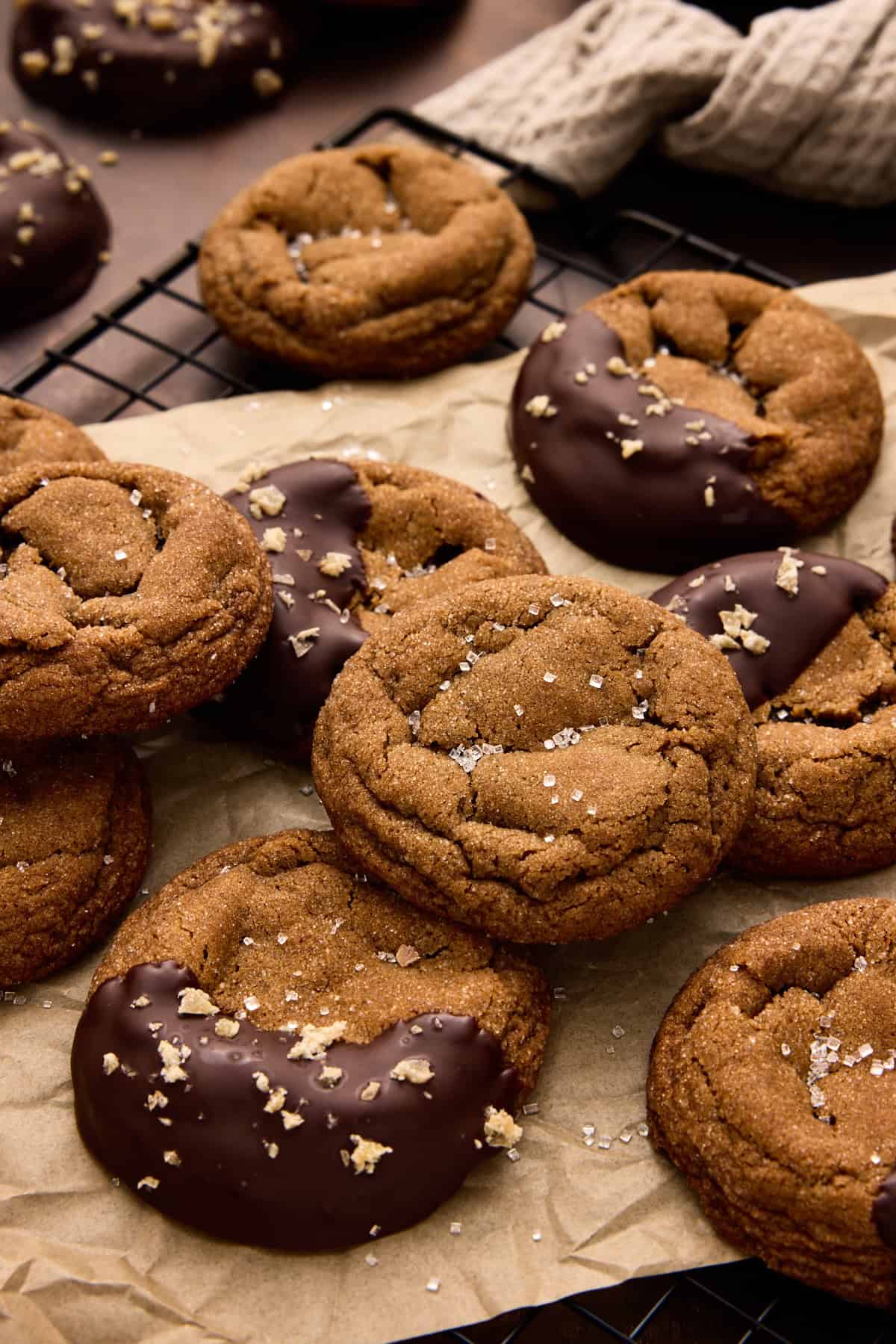 Chewy Ginger Molasses Cookies on parchment paper with candied ginger and chocolate.