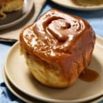 Close up shot of gooey caramel roll on a small plate.