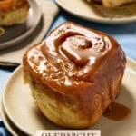 Close up of gooey caramel roll on small cream plate.