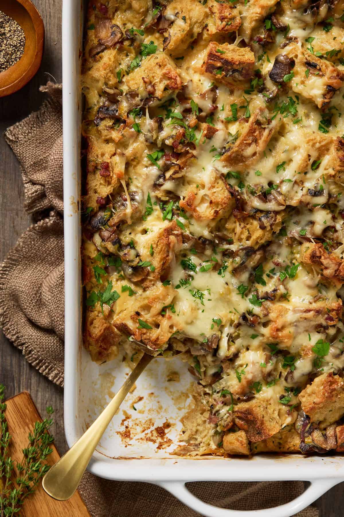 Mushroom & Leek Bread Pudding in a white casserole dish with a corner scooped out.