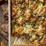Savory mushroom and leek bread pudding in a white casserole dish with a corner scooped out.