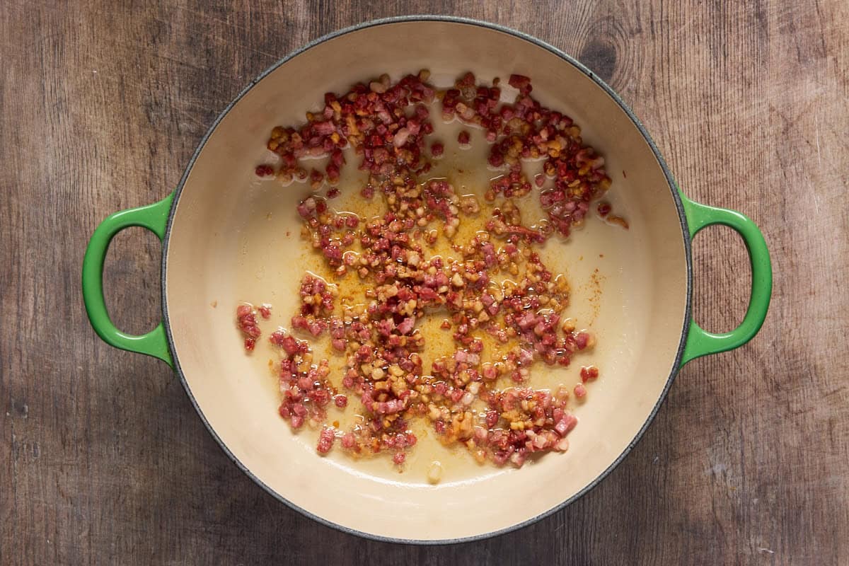 Green dutch oven with sauteed pancetta.