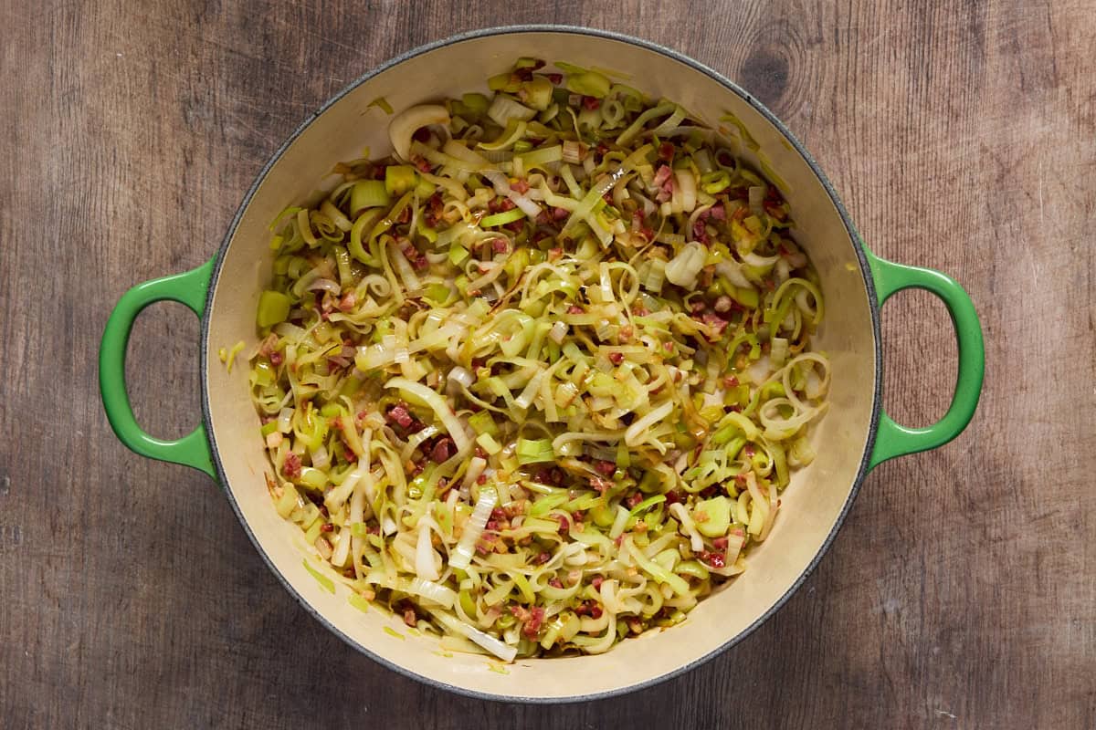 Green dutch oven with sauteed leeks and pancetta.
