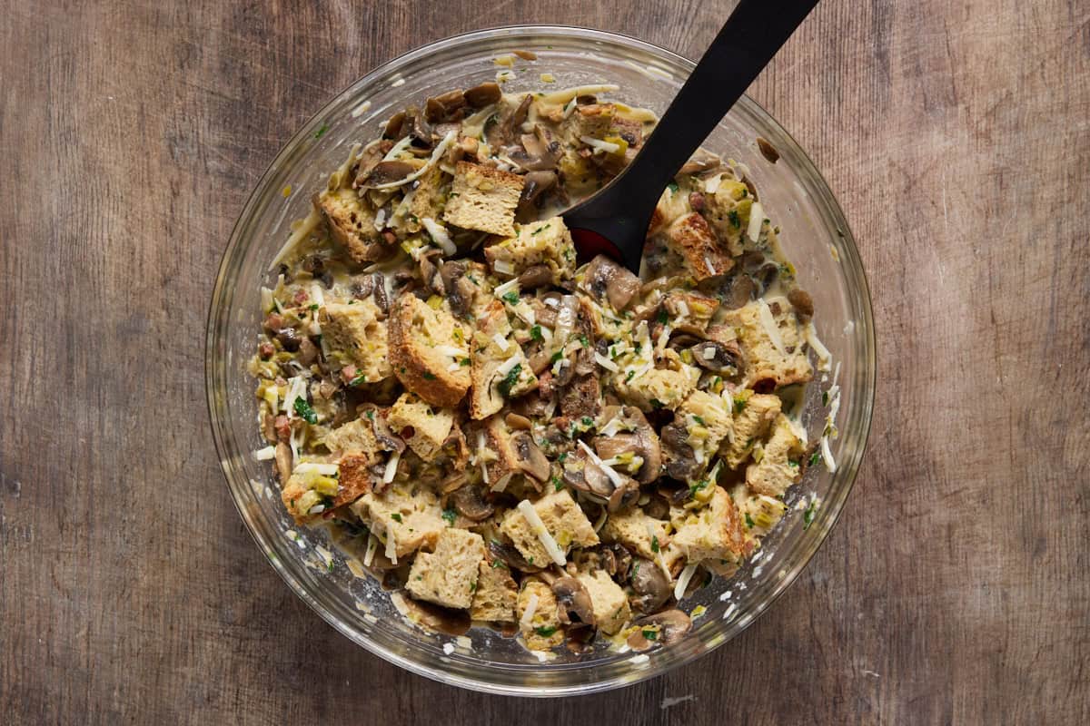 Bread pudding mix with mushrooms and leeks in a glass bowl.