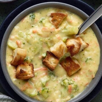 Square image of broccoli cheddar soup in a bowl with croutons.