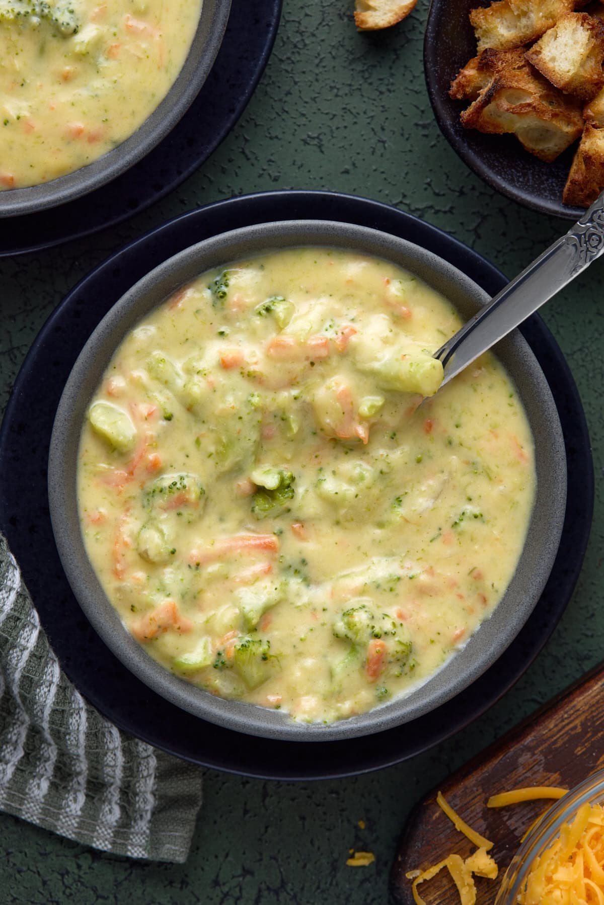 Broccoli Cheddar soup in a bowl with croutons and a spoon.