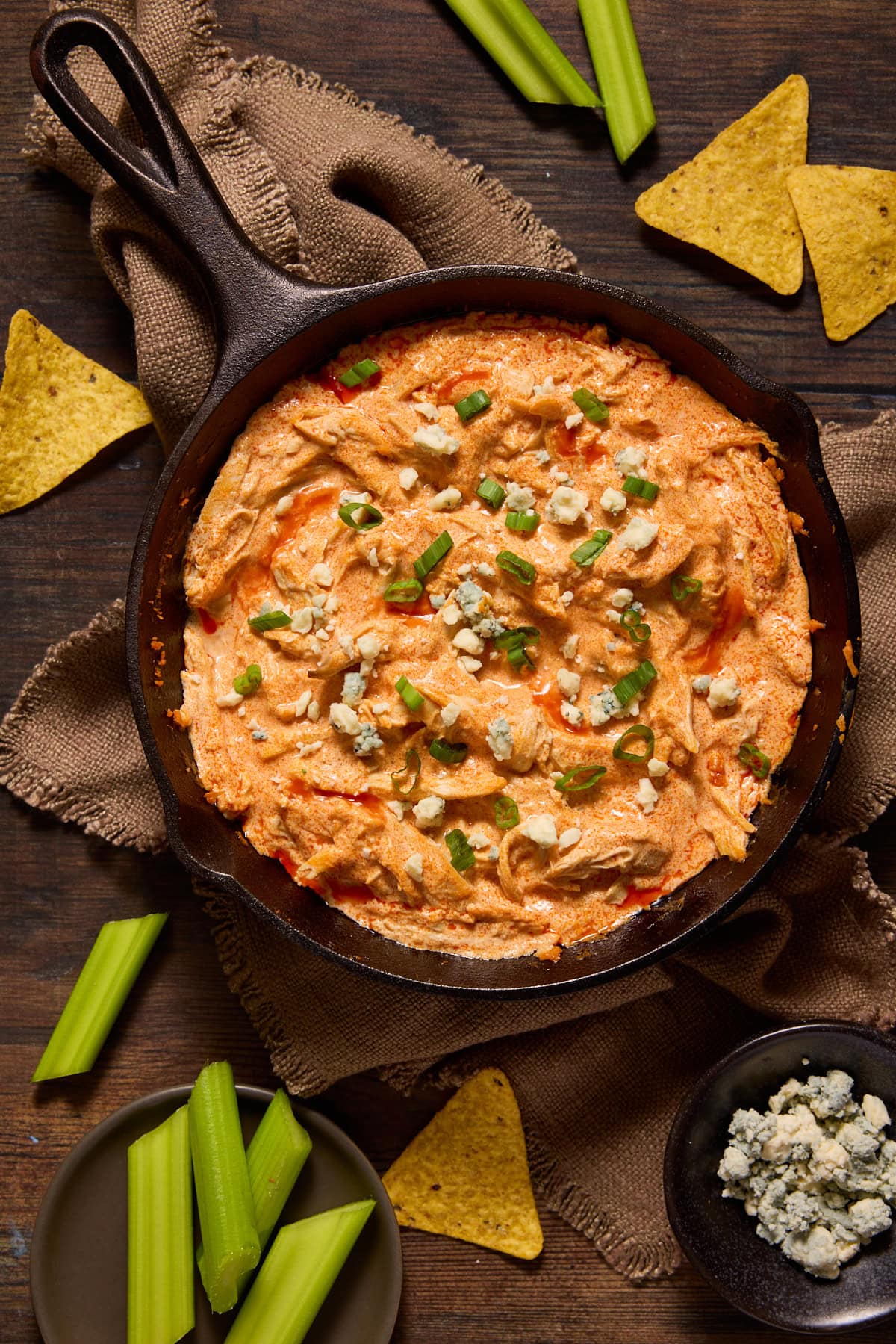 Buffalo Chicken Dip in a cast iron skillet with blue cheese and scallions on top.
