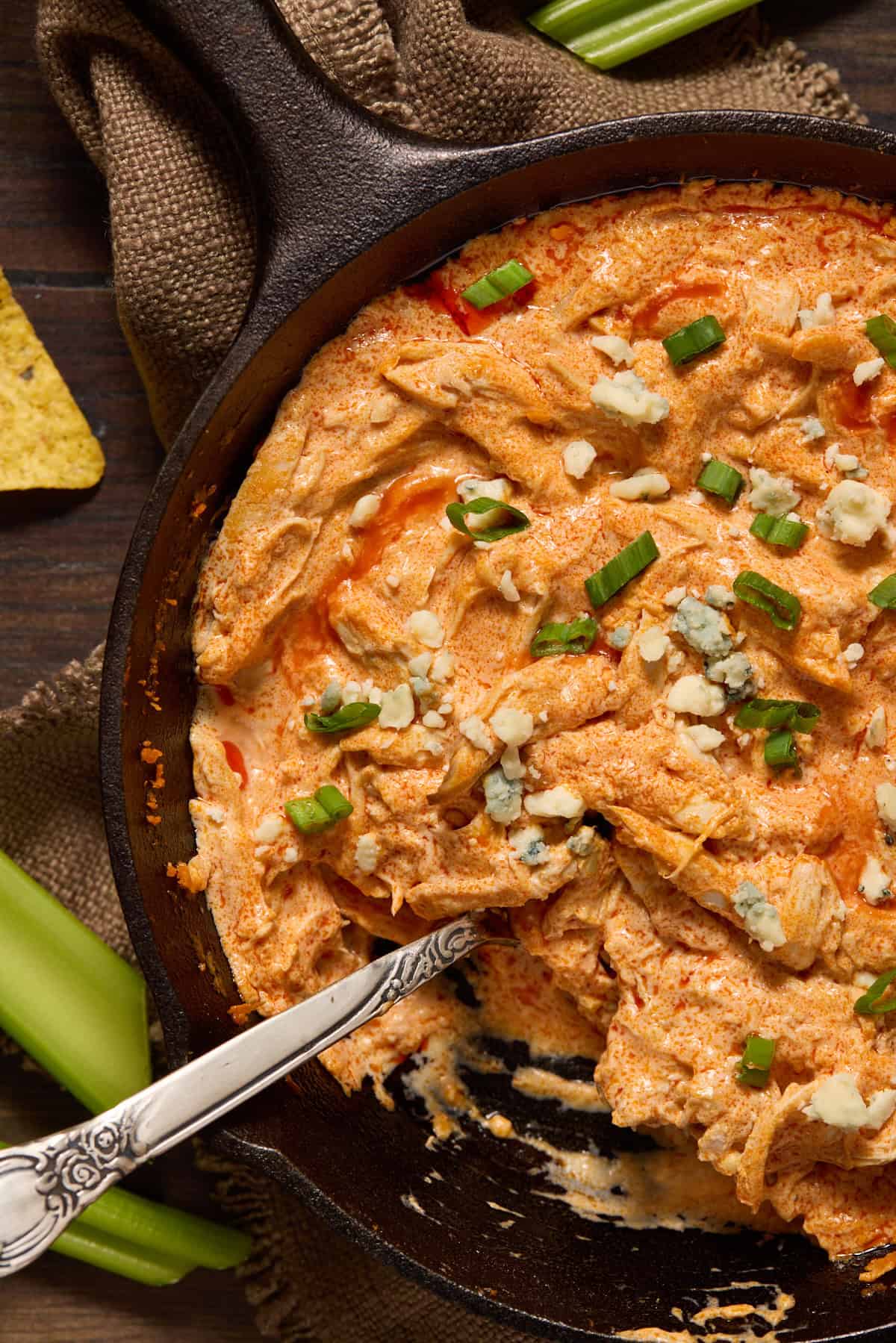 Buffalo chicken dip in cast iron pan with a spoonful of dip removed.