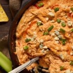 Buffalo chicken dip with a spoon for serving and celery sticks.
