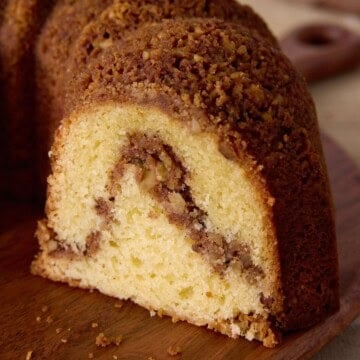Sliced cinnamon swirl sour cream coffee cake on a wooden cutting board.