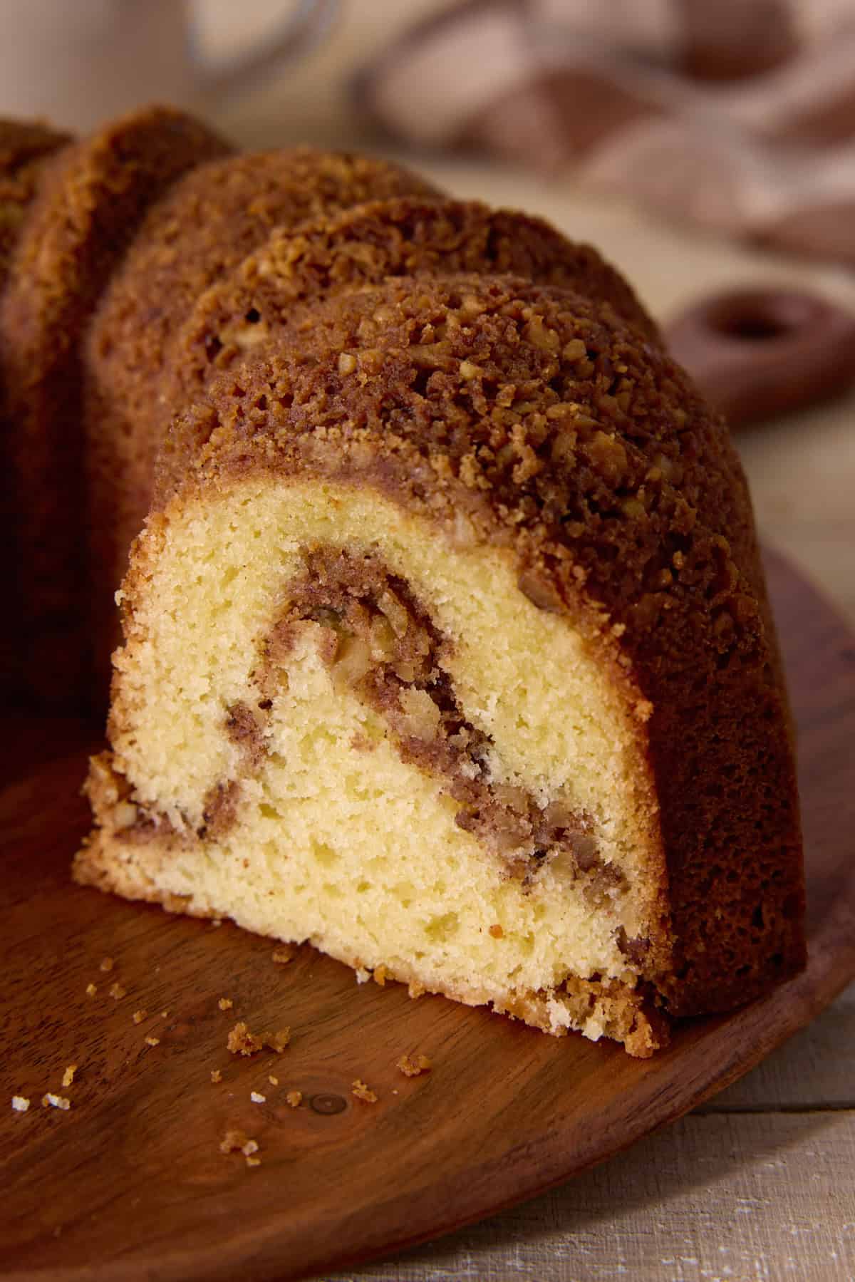 Sliced cinnamon swirl sour cream coffee cake on a wooden cutting board.