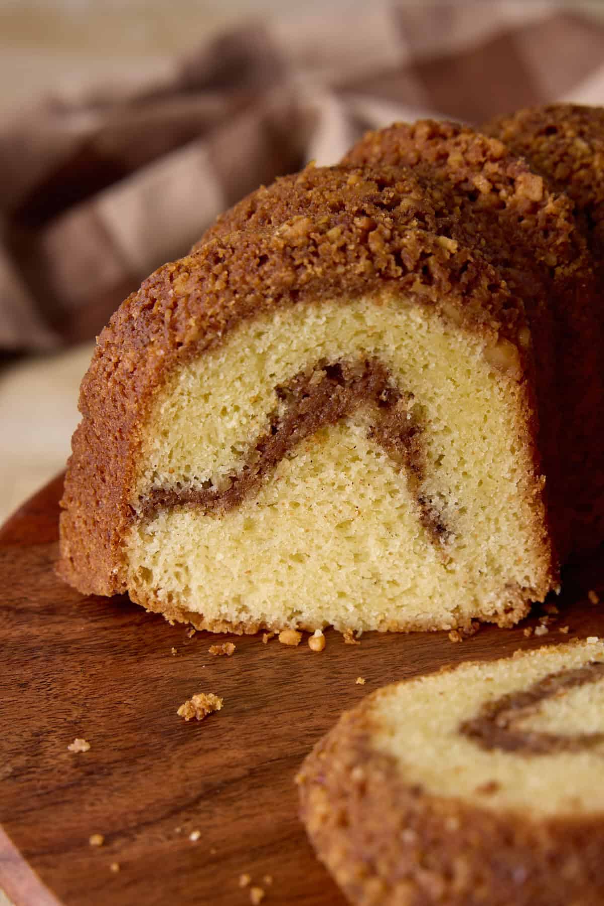 Sliced cinnamon swirl sour cream coffee cake on a wooden cutting board.
