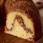 Sliced cinnamon swirl sour cream coffee cake on a wooden cutting board.
