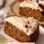 Slice of single layer carrot cake with brown butter cream cheese frosting on a stack of plates along with other slices in the background.