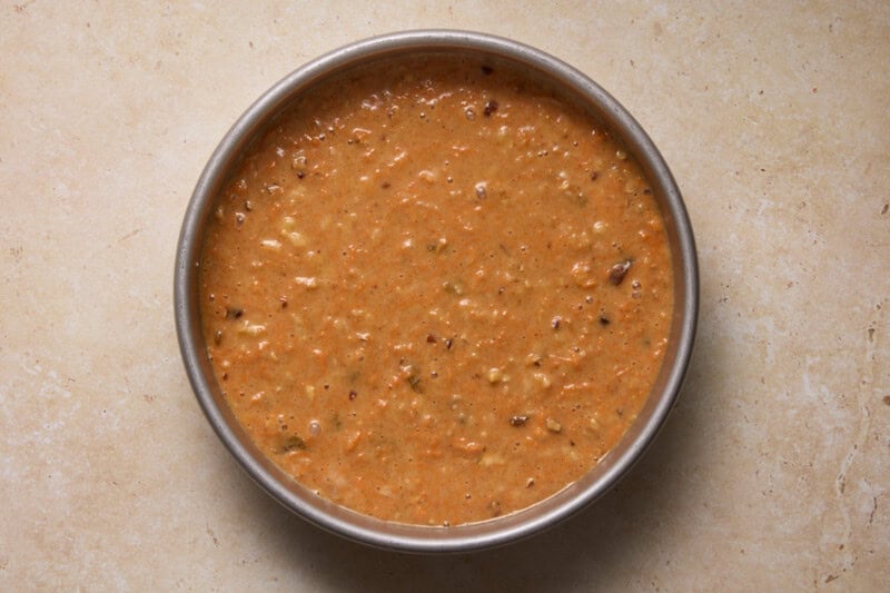 Carrot cake batter in a round metal cake pan.