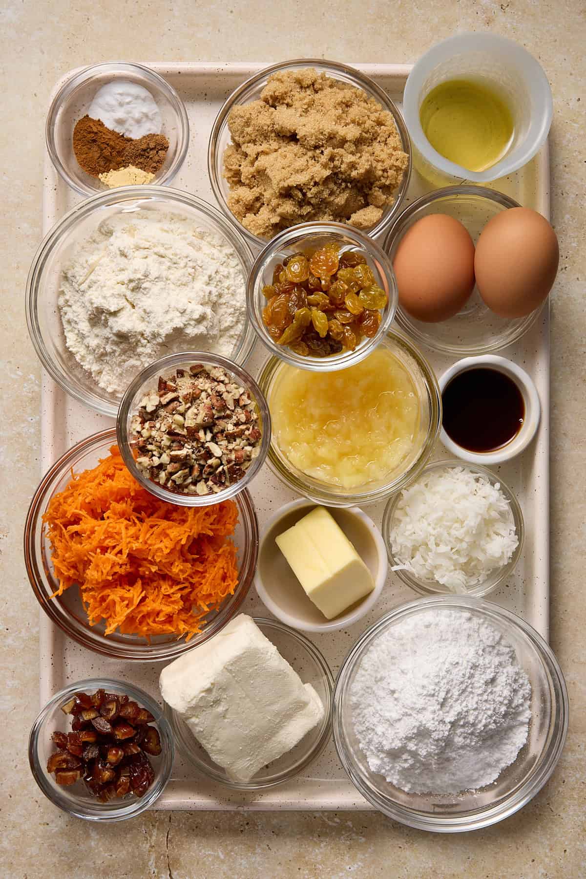 Ingredients needed to make a single layer carrot cake, including carrots, brown sugar, coconut, pecans and cream cheese.