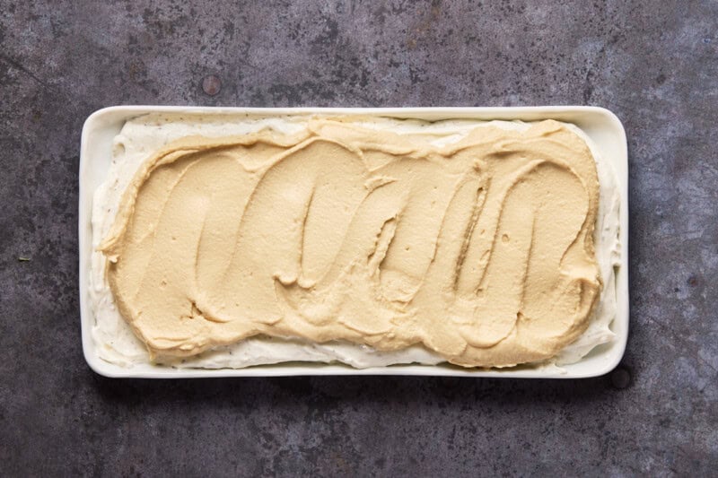 Seasoned cream cheese and hummus layered on a white platter.