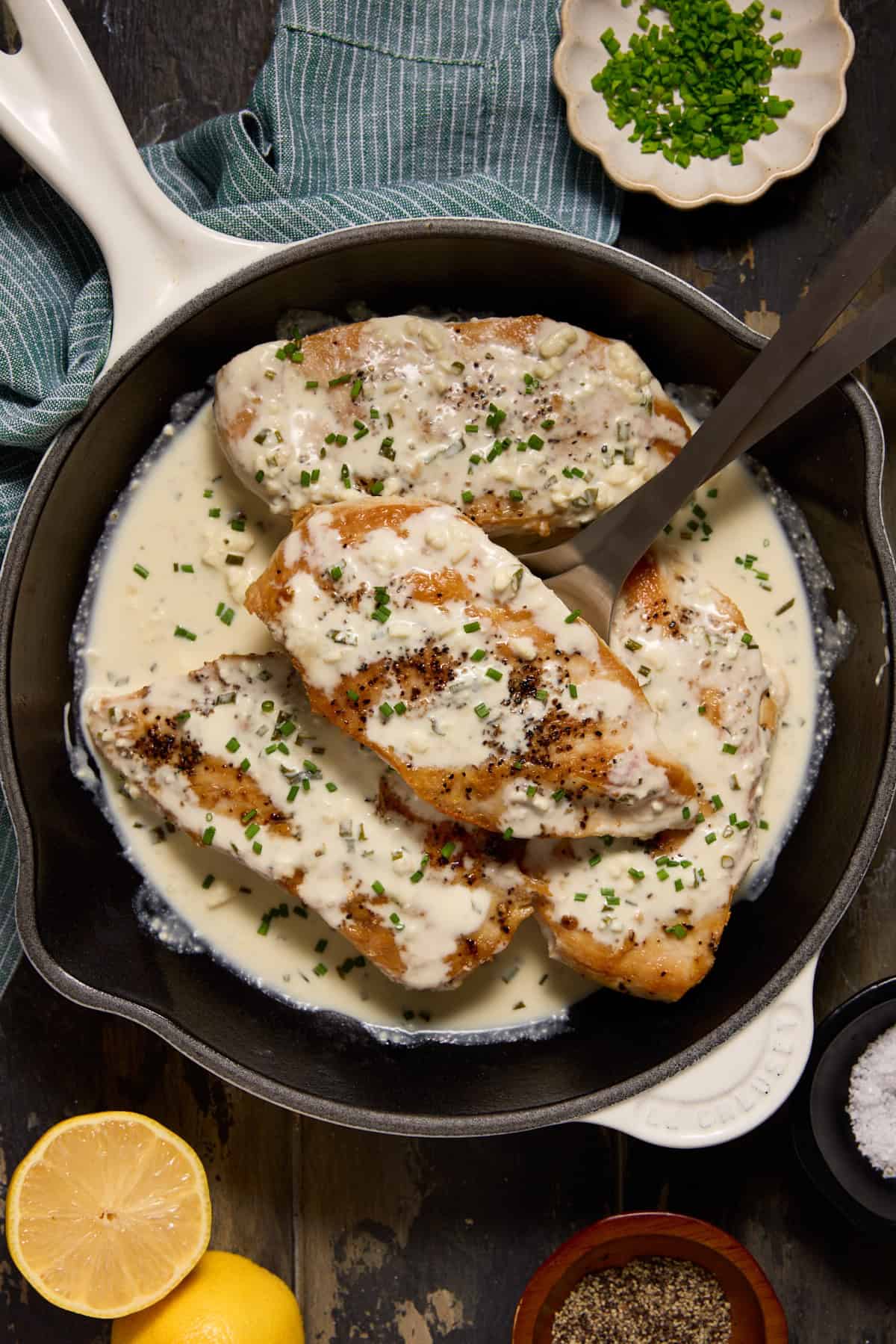 Seared chicken breasts in a skillet with creamy feta cheese sauce.