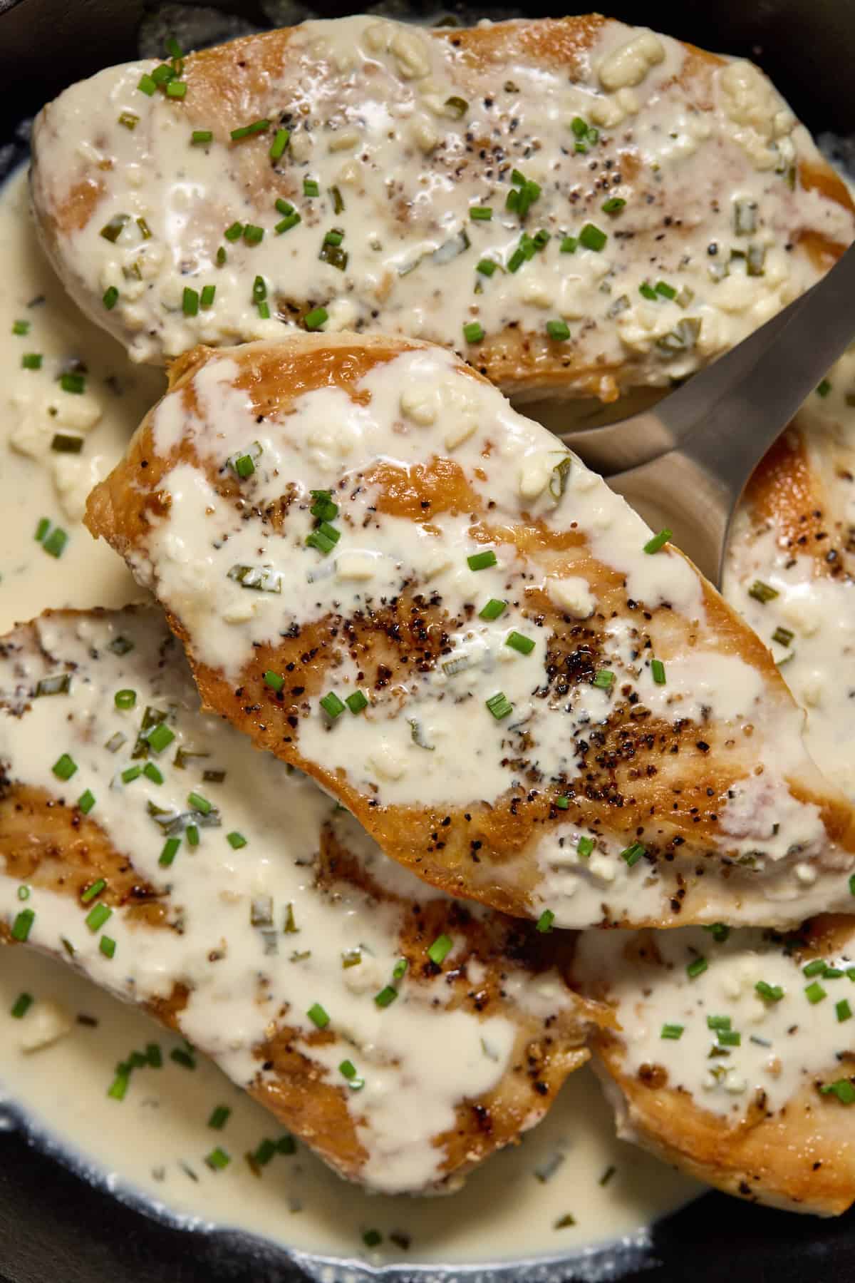 Seared chicken breasts in a skillet with creamy feta cheese sauce.