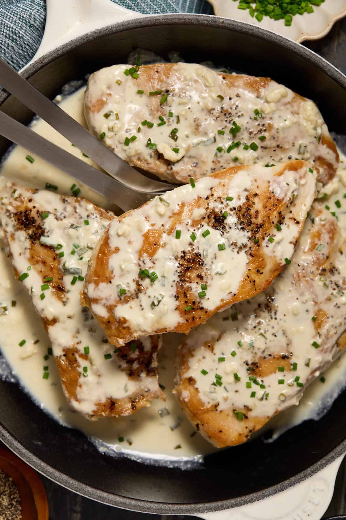 Seared chicken breasts in a skillet with creamy feta cheese sauce.