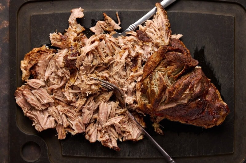 Pork shoulder on cutting board partly shredded.