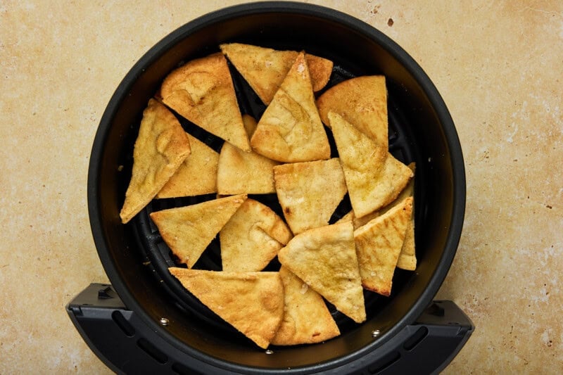 Air fryer pita chips in the bowl of an air fryer.