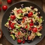 Greek Quinoa salad with Tomatoes, raw quinoa and a lemon half.