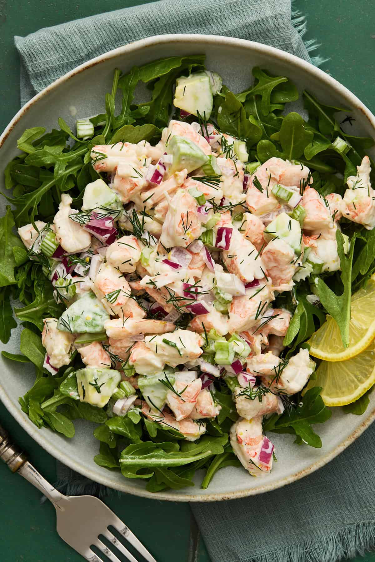 Shrimp Salad on top of arugula on a plate with a fork and napkin.