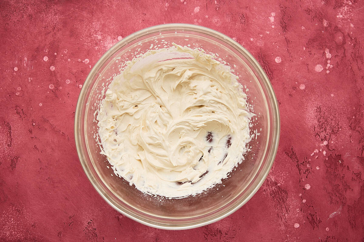 Heavy cream whipped with powdered sugar in a glass bowl.