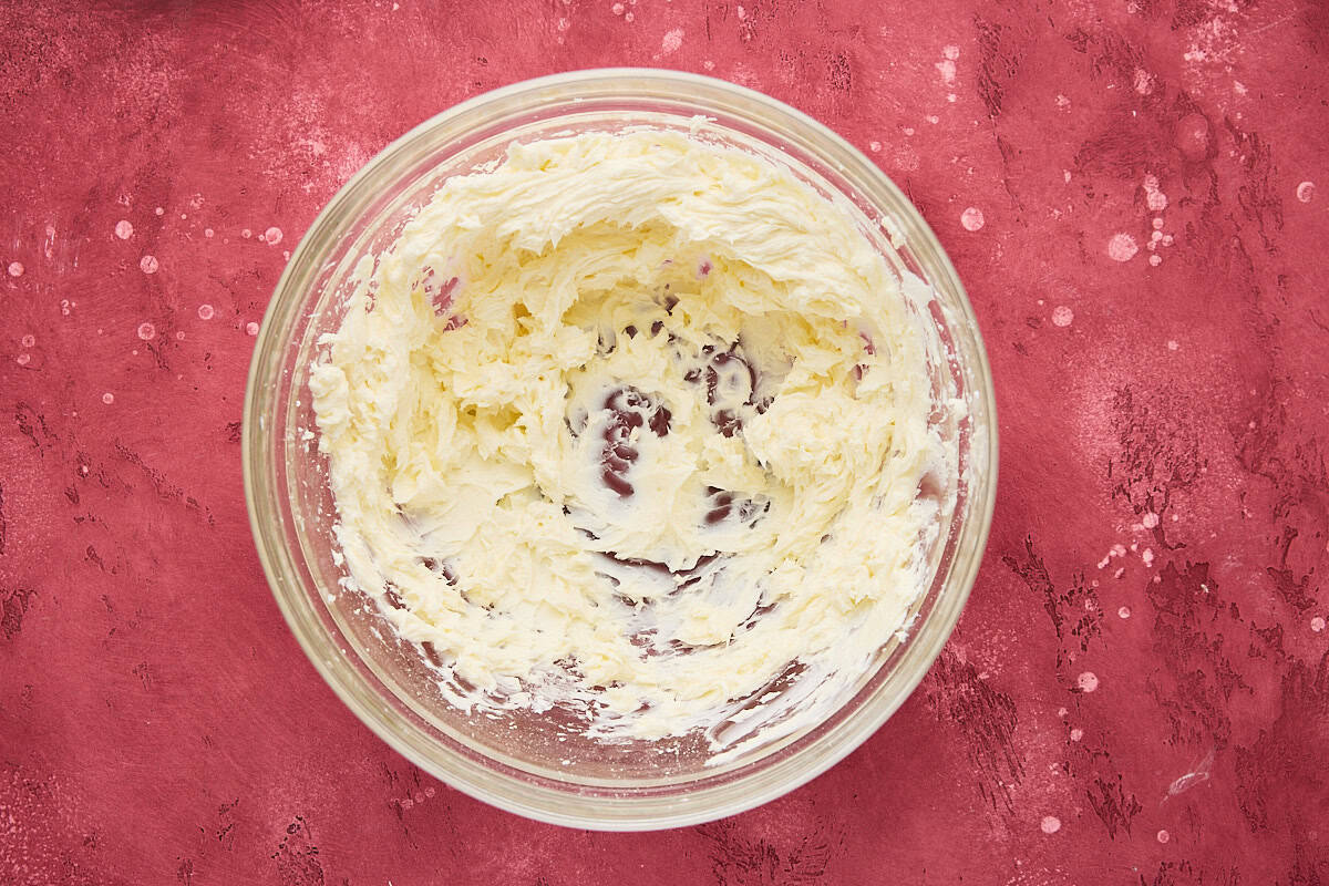 Cream cheese and powdered sugar whipped together with powdered sugar in a glass bowl.