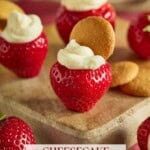 Cheesecake stuffed strawberries on a wooden cutting board.