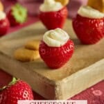 Cheesecake stuffed strawberries on a wooden cutting board. Some berries are topped with a mini Nilla wafer.