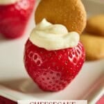 A cheesecake stuffed strawberry topped with a mini Nilla wafer on a white plate.