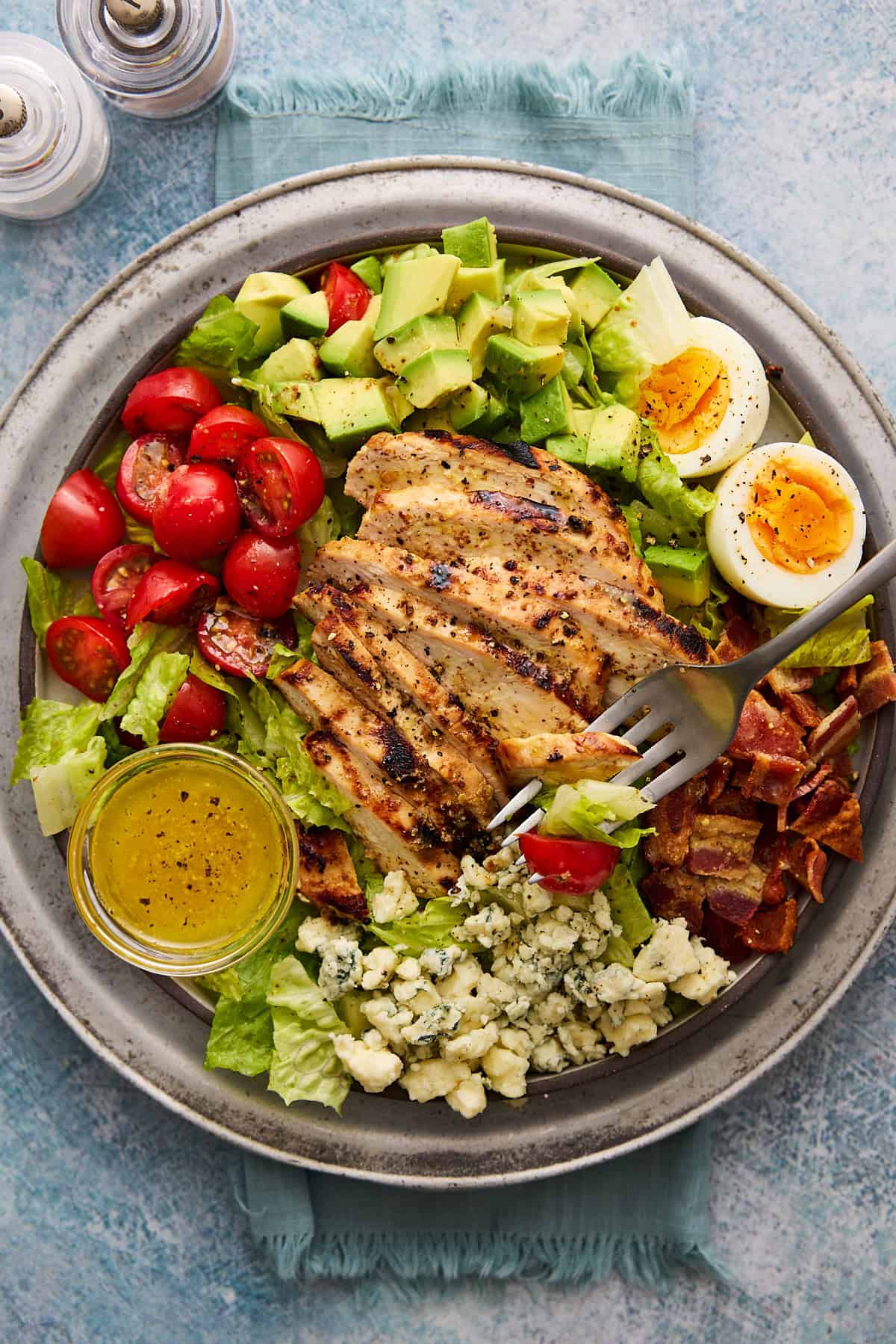 Grilled Chicken Cobb Salad on a plate with a blue backgorund.