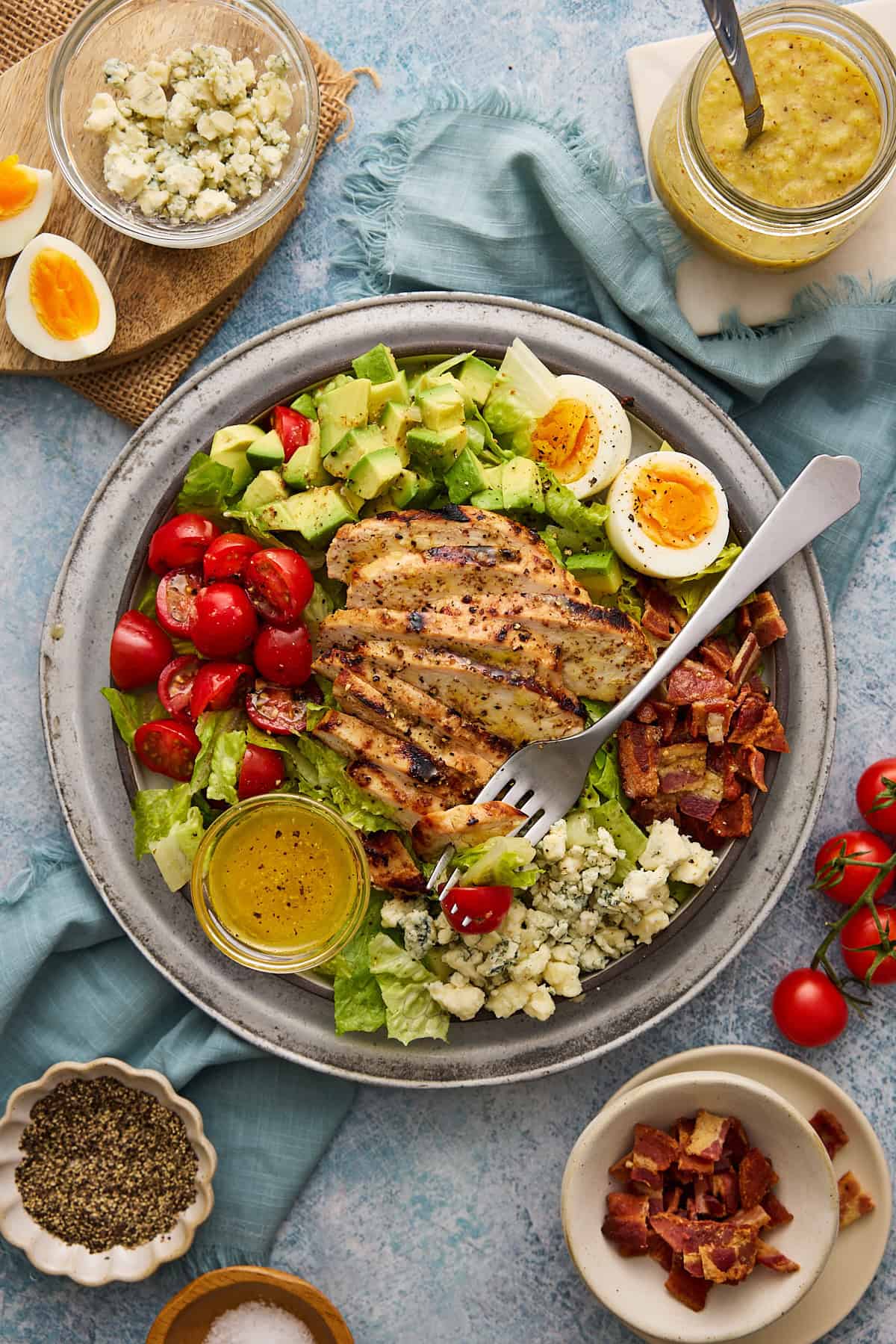 Chicken Cobb Salad on a silver plate with extra ingredients on board as props.