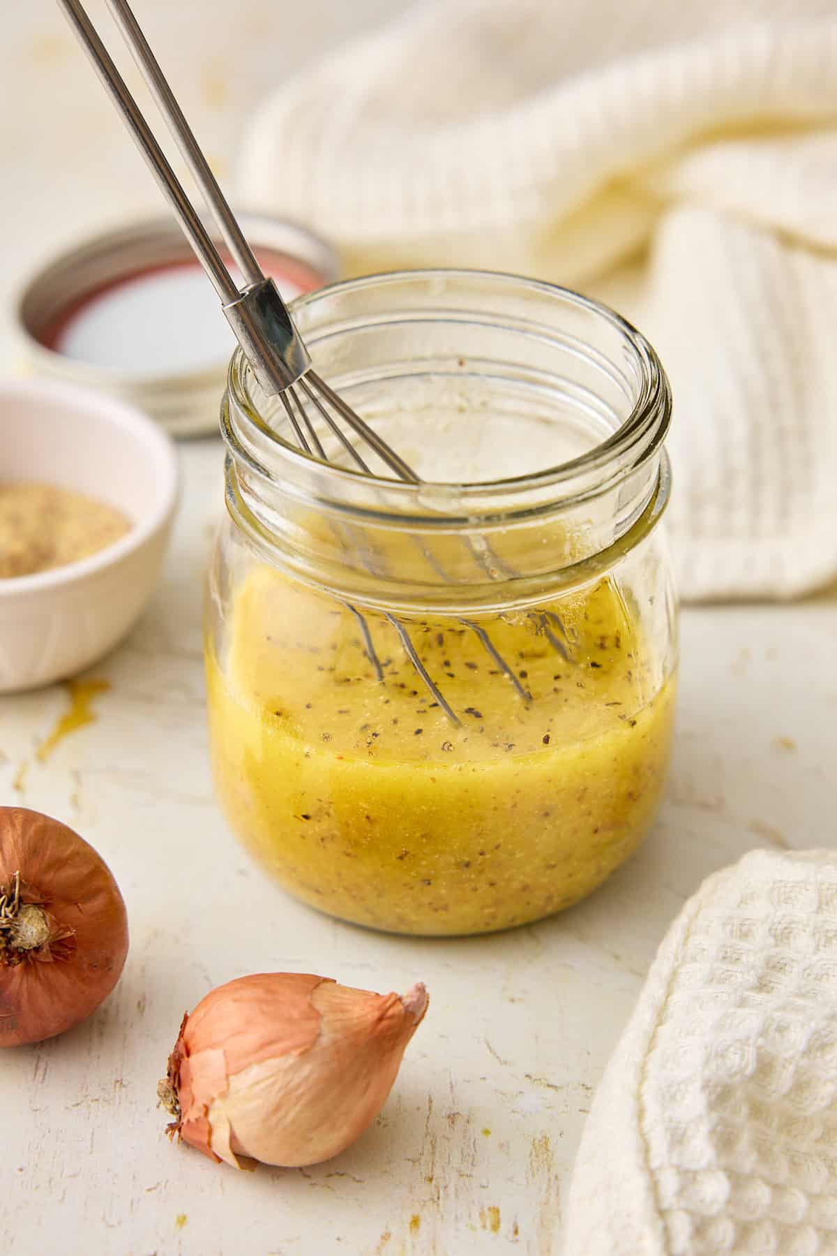 Dijon vinaigrette in a small jar with a whisk.