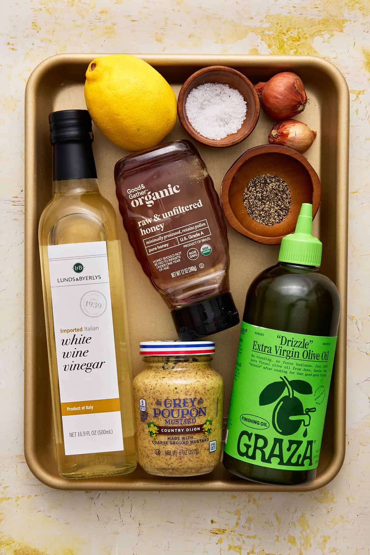 Ingredients needed to make dijon vinaigrette on a gold sheet pan.