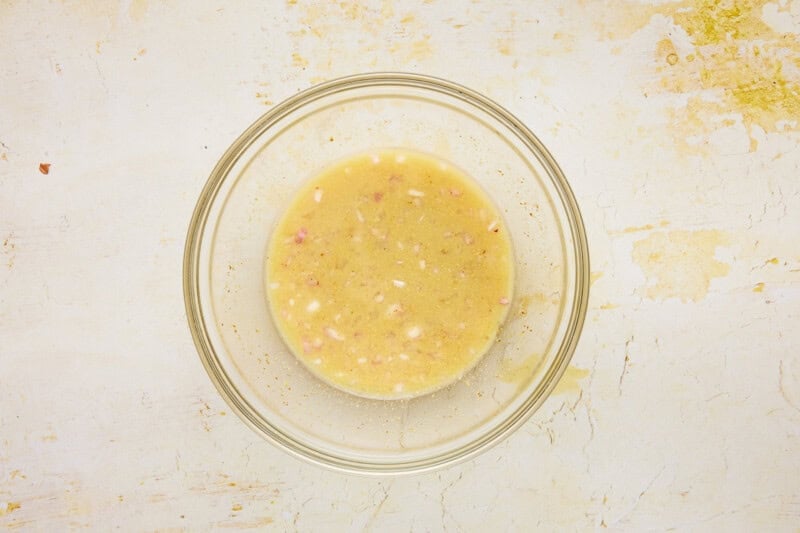 glass bowl filled with white wine vinegar, shallots, mustard, honey and lemon juice.