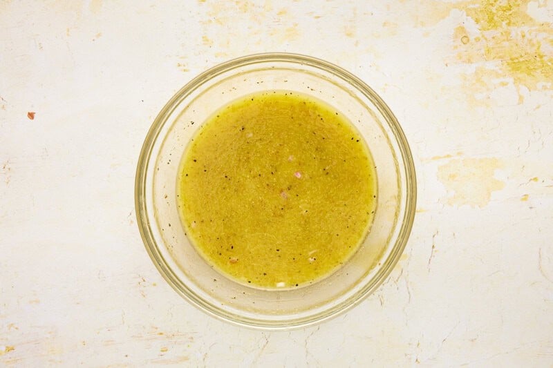 Dijon vinaigrette whisked in a bowl with pepper.
