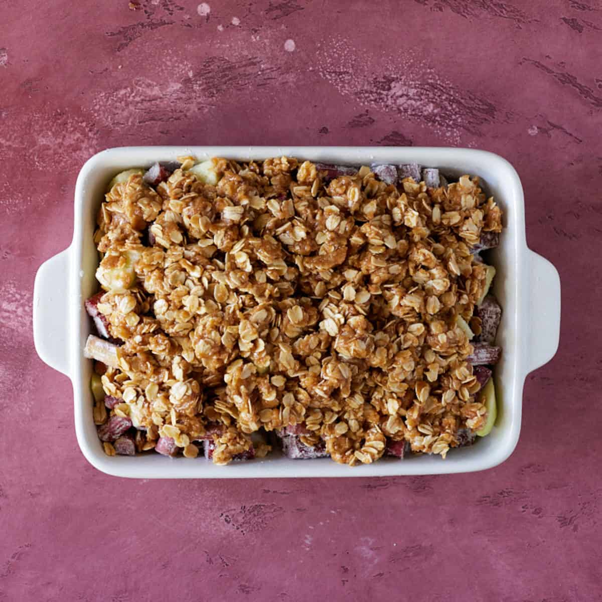 Streusel topping on apples and rhubarb ready to bake.