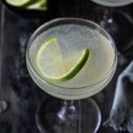 Two coupe glasses filled with classic daiquiri cocktails and garnished with lime wheels.
